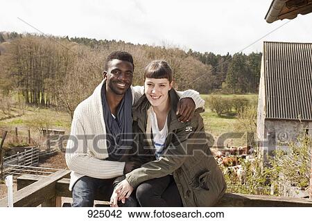 A young couple sitting on a balcony railing View Large Photo Image Stock Image - A young couple sitting on a balcony railing. Fotosearch