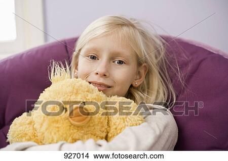 A young girl sitting in a papasan chair hugging a stuffed bird View Large Photo Image Picture - A young girl sitting in a papasan chair hugging a stuffed bird. Fotosearch