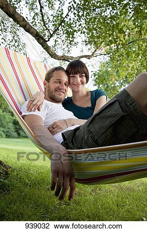 A young happy couple lying in a hammock together View Large Photo Image Stock Image - A young happy couple lying in a hammock together. Fotosearch