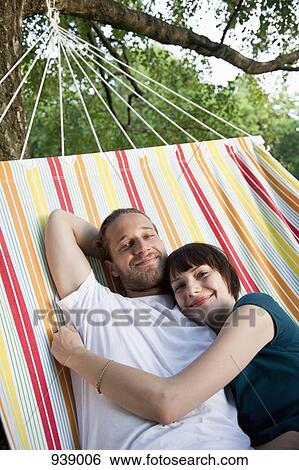 A young happy couple lying in a hammock together View Large Photo Image Stock Photograph - A young happy couple lying in a hammock together. Fotosearch