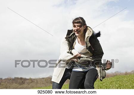 Stock Image - A young man catching his girlfriend after chasing her. Fotosearch