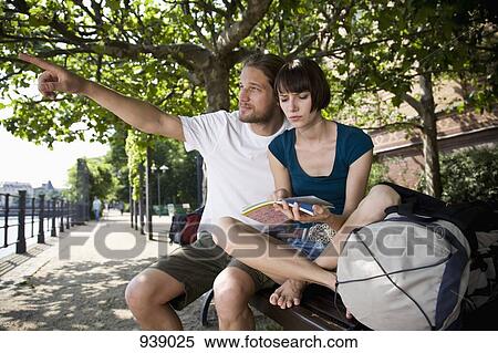 A young man pointing, while his girlfriend looks at a map with uncertainty View Large Photo Image Stock Photography - A young man pointing, while his girlfriend looks at a map with uncertainty. Fotosearch