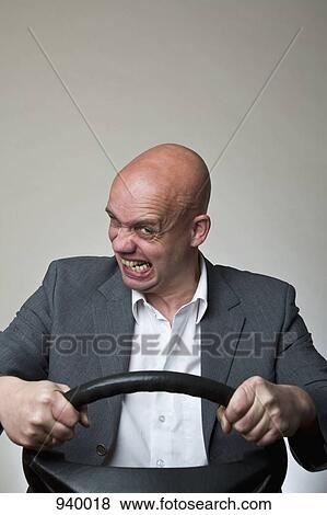 An angry man behind a car steering wheel View Large Photo Image Stock Photo - An angry man behind a car steering wheel. Fotosearch