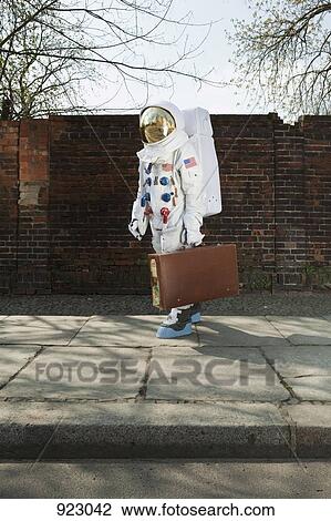 An astronaut carrying a suitcase and walking on a city sidewalk View Large Photo Image Stock Image - An astronaut carrying a suitcase and walking on a city sidewalk. Fotosearch