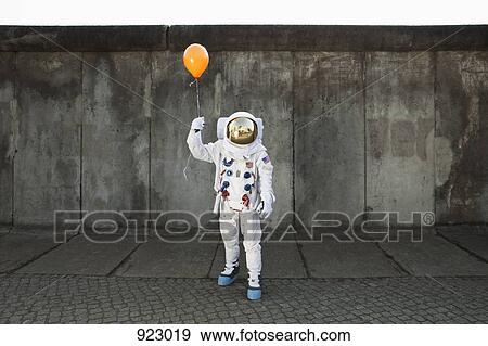 Stock Photo - An astronaut on a city sidewalk holding a balloon. Fotosearch