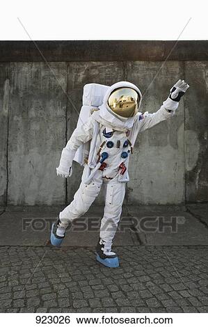 Stock Photograph - An astronaut on a city sidewalk pretending to take off in flight. Fotosearch