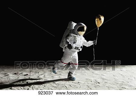 An astronaut on the moon holding a heart shaped helium balloon View Large Photo Image Stock Photo - An astronaut on the moon holding a heart shaped helium balloon. Fotosearch