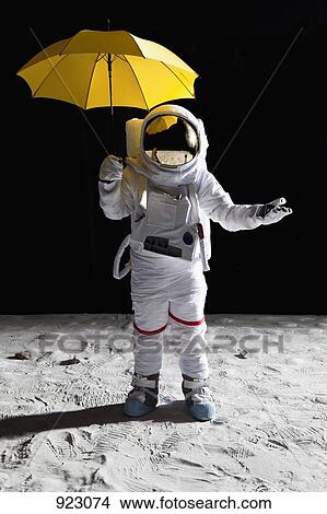 Picture - An astronaut on the moon holding an umbrella. Fotosearch