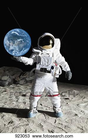 Stock Image - An astronaut on the moon's surface pretending to hold the earth . Fotosearch