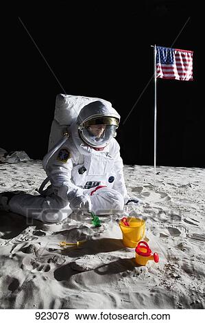 Stock Photo - An astronaut playing with a sand pail and shovel on the moon. Fotosearch