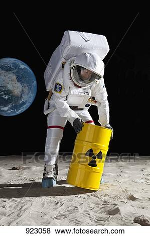 Stock Photo - An astronaut rolling a drum of toxic material on the moon surface. Fotosearch