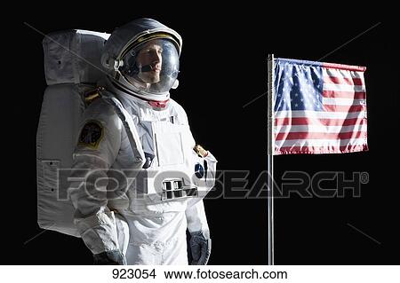 An astronaut with a serious expression standing next to an American flag View Large Photo Image Picture - An astronaut with a serious expression standing next to an American flag. Fotosearch