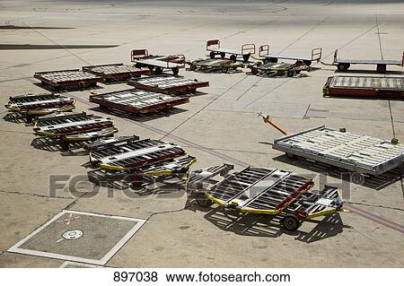 Stock Photo - Baggage trailers on an airport tarmac. Fotosearch