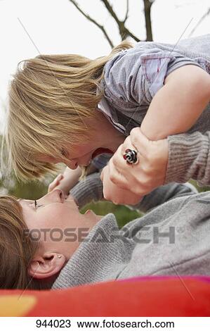 Detail of a woman lying down and holding her son above her View Large Photo Image Stock Image - Detail of a woman lying down and holding her son above her. Fotosearch