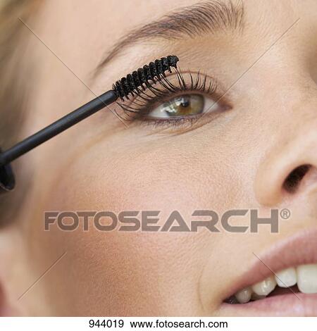 Stock Photo - Detail of a young woman applying mascara. Fotosearch