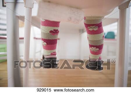 Stock Photography - Low section of a baby girl sitting on a chair. Fotosearch