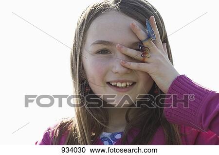 Stock Image - Portrait of a girl covering her eye with her hand. Fotosearch