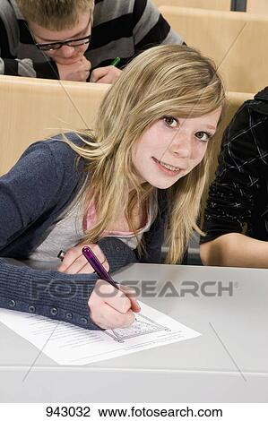 Portrait of a teenager doing a worksheet in class, smiling at camera View Large Photo Image Stock Image - Portrait of a teenager doing a worksheet in class, smiling at camera. Fotosearch