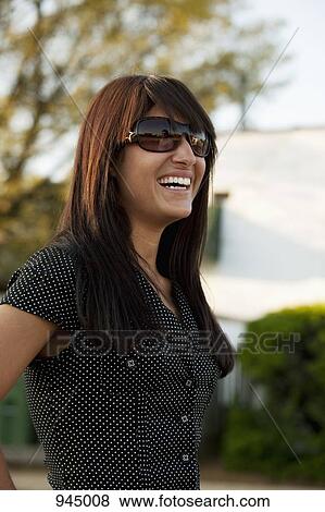 Portrait of a young woman wearing sunglasses and laughing View Large Photo Image Stock Photo - Portrait of a young woman wearing sunglasses and laughing. Fotosearch