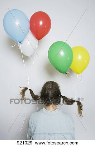 Stock Photo - Rear view of a girl with helium balloons tied to her pigtails. Fotosearch