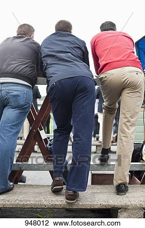 Rear view of three male spectators at a horse racing track View Large Photo Image Stock Image - Rear view of three male spectators at a horse racing track. Fotosearch