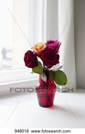 Stock Photo - Roses in a vase on a windowsill. Fotosearch