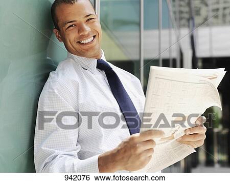 Stock Photograph - Smiling businessman holding a newspaper . Fotosearch
