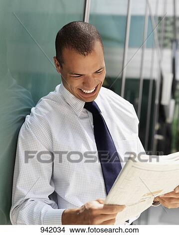 Picture - Smiling businessman reading a newspaper. Fotosearch