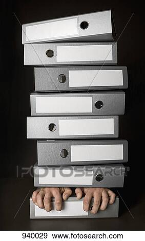Stock Photo - The hands of a man under a stack of folders. Fotosearch