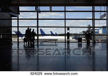 Three business people walking by a window of an airport, silhouette View Large Photo Image Stock Photo - Three business people walking by a window of an airport, silhouette. Fotosearch