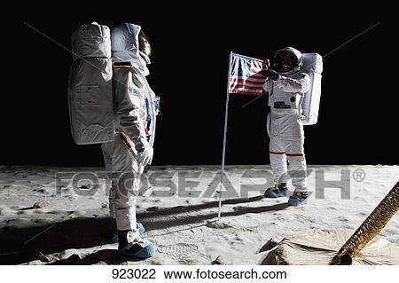 Stock Image - Two astronauts on the moon, an American flag in between them. Fotosearch
