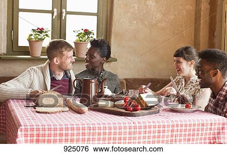 Stock Photograph - Two couples enjoying a simple rustic meal. Fotosearch