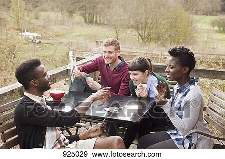 Two couples playing cards, outdoors View Large Photo Image Stock Photo - Two couples playing cards, outdoors. Fotosearch