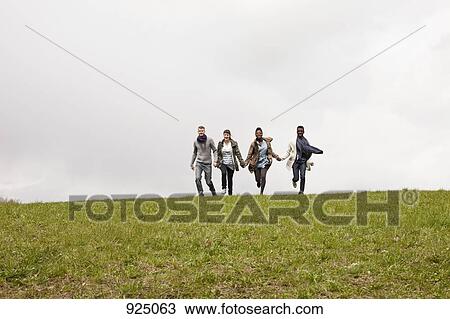 Two couples running down a hill while holding hands View Large Photo Image Stock Image - Two couples running down a hill while holding hands. Fotosearch