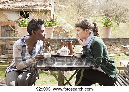Stock Image - Two women having coffee and gossiping. Fotosearch