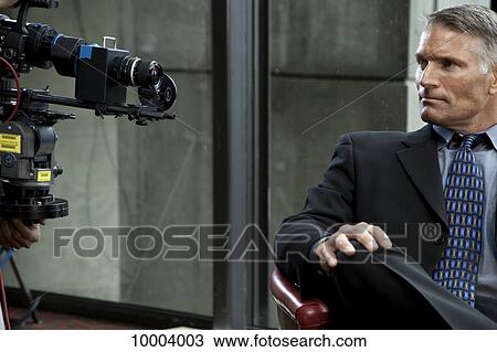 Stock Image - A businessman in front of a video camera. Fotosearch