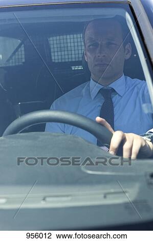 Stock Image - A businessman in his car, looking through windshield. Fotosearch