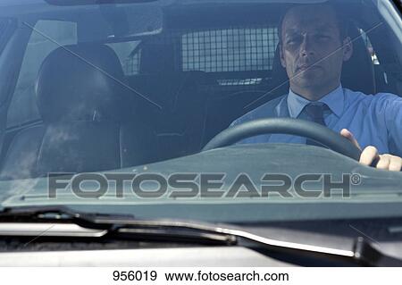 Stock Photo - A businessman in his car, looking through windshield. Fotosearch