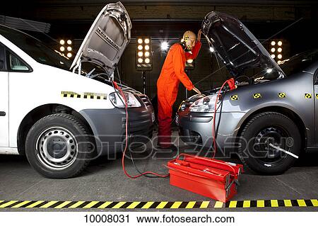 Stock Image - A crash test dummy using jumper cables with two cars. Fotosearch