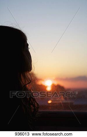 A girl looking out a window at sunset View Large Photo Image Stock Image - A girl looking out a window at sunset. Fotosearch