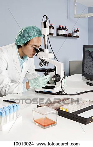 A lab technician looking into a microscope in a laboratory View Large Photo Image Picture - A lab technician looking into a microscope in a laboratory. Fotosearch