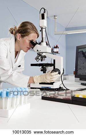 A lab technician looking into a microscope in a laboratory View Large Photo Image Stock Photography - A lab technician looking into a microscope in a laboratory. Fotosearch