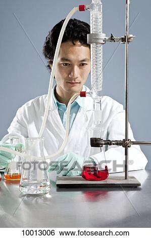 A lab technician watching a laboratory condenser distill liquid into a beaker View Large Photo Image Stock Photograph - A lab technician watching a laboratory condenser distill liquid into a beaker. Fotosearch