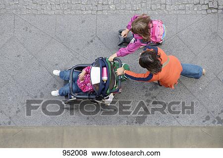 Stock Photo - A mother and daughter pushing another daughter in a stroller. Fotosearch