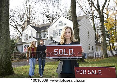 Stock Photo - A real estate agent holding a SOLD sign. Fotosearch