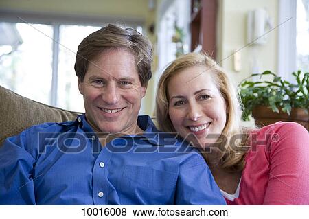 Stock Photo - A smiling couple sitting on a couch. Fotosearch
