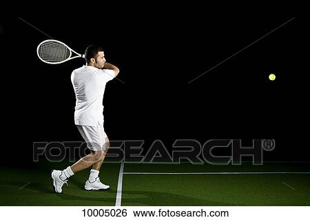 Stock Photograph - A tennis player about to a hit a ball, studio shot, portrait. Fotosearch