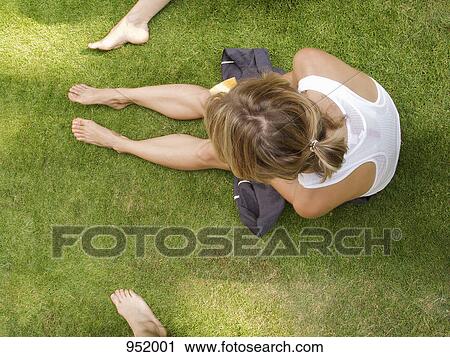 Stock Image - A woman sitting on grass, directly above. Fotosearch