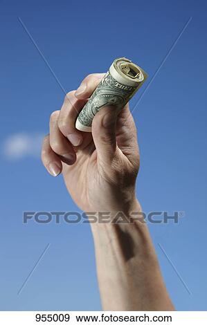 Stock Photo - Hand holding roll of dollars. Fotosearch