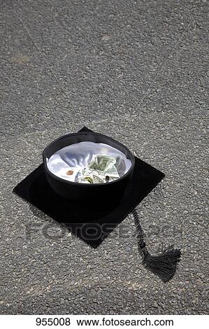 Mortarboard with money in it on asphalt View Large Photo Image Stock Photo - Mortarboard with money in it on asphalt. Fotosearch